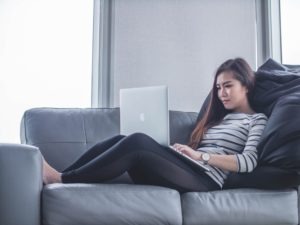 woman on couch with laptop researching how to become a surrogate
